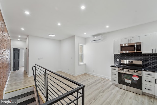 kitchen with light hardwood / wood-style flooring, an AC wall unit, decorative backsplash, white cabinets, and appliances with stainless steel finishes