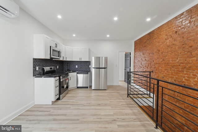 kitchen with white cabinetry, stainless steel appliances, brick wall, and light hardwood / wood-style flooring