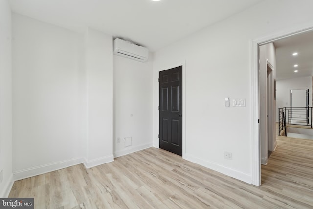 spare room featuring light wood-type flooring and an AC wall unit