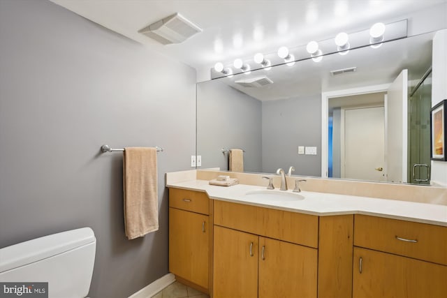 bathroom with toilet, vanity, and tile patterned floors