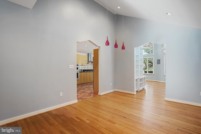 unfurnished room featuring a towering ceiling and light hardwood / wood-style flooring