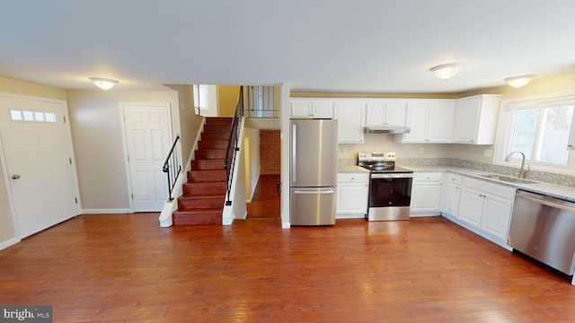 kitchen with appliances with stainless steel finishes, white cabinets, sink, and wood-type flooring