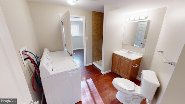 bathroom with toilet, vanity, a shower, washer / dryer, and hardwood / wood-style flooring