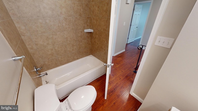 bathroom featuring toilet, wood-type flooring, and tiled shower / bath