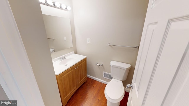 bathroom with toilet, vanity, and hardwood / wood-style floors