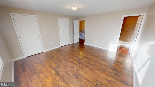 unfurnished bedroom with ensuite bathroom and dark wood-type flooring