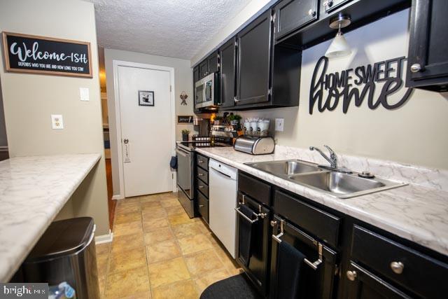 kitchen with sink, stainless steel appliances, and a textured ceiling