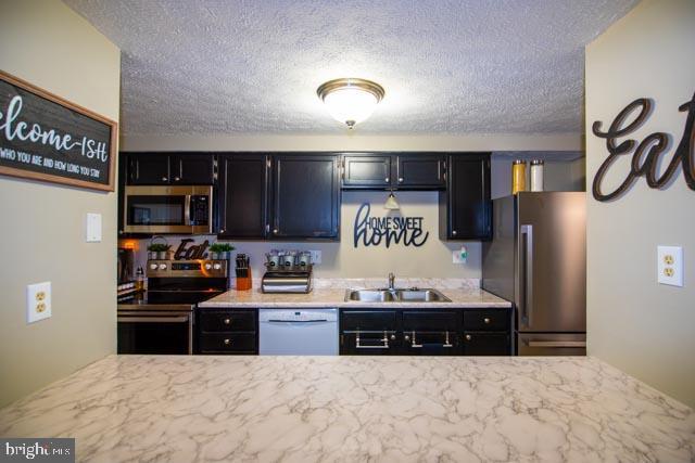 kitchen with stainless steel appliances, a textured ceiling, and sink