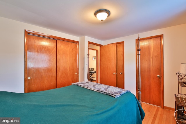 bedroom with light hardwood / wood-style flooring and two closets