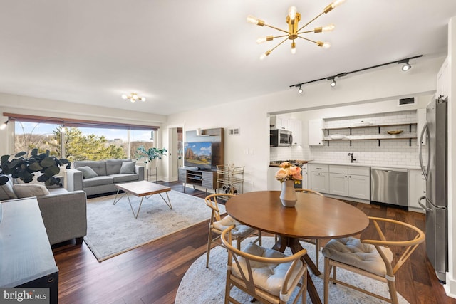 dining space with dark hardwood / wood-style flooring, sink, and a notable chandelier