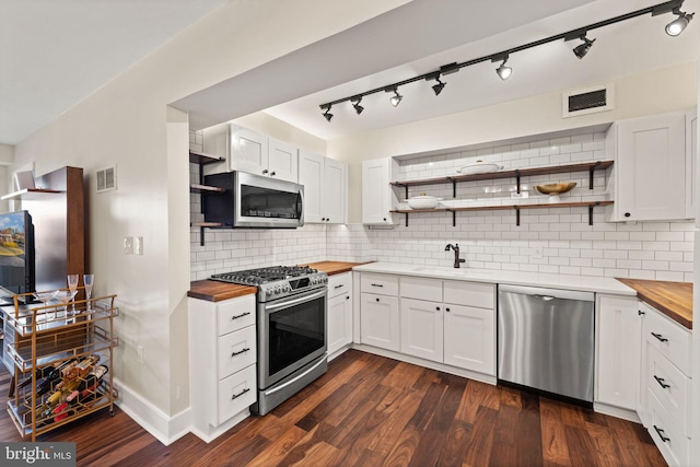 kitchen with stainless steel appliances, white cabinetry, and butcher block counters