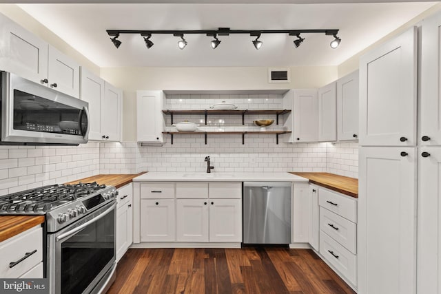 kitchen featuring stainless steel appliances, wooden counters, and white cabinets