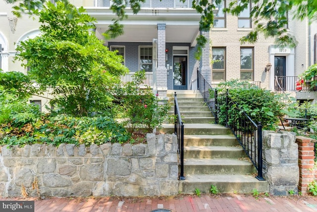 property entrance featuring a porch and brick siding