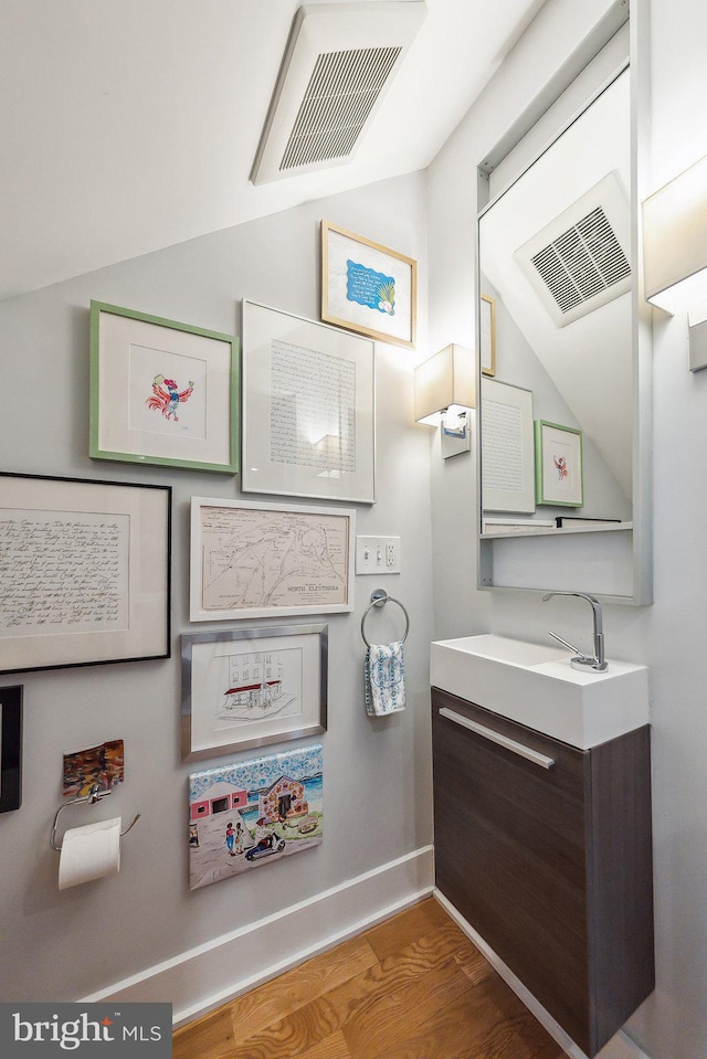 bathroom featuring baseboards, visible vents, vaulted ceiling, and wood finished floors