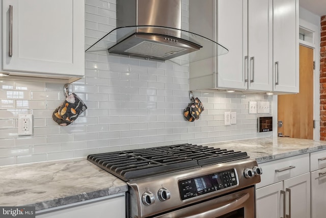 kitchen with white cabinetry, stainless steel gas range, range hood, and light stone counters