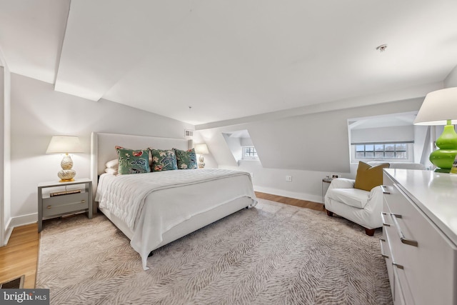 bedroom featuring lofted ceiling, light wood finished floors, and baseboards