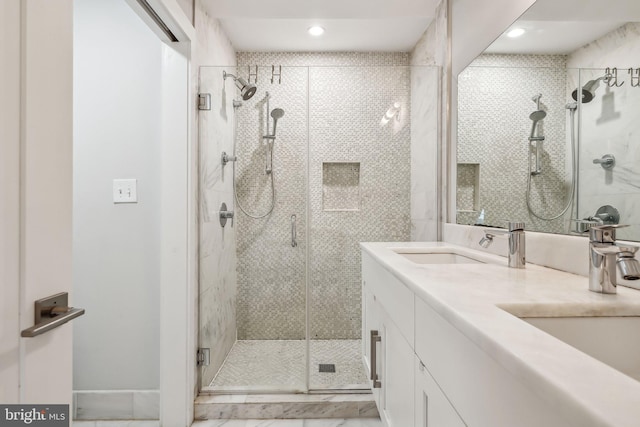 full bathroom with double vanity, a stall shower, and a sink