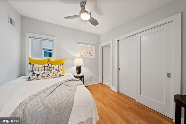 bedroom with baseboards, visible vents, a ceiling fan, wood finished floors, and a closet