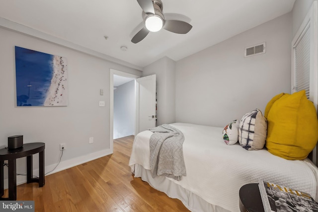 bedroom with baseboards, ceiling fan, visible vents, and wood finished floors