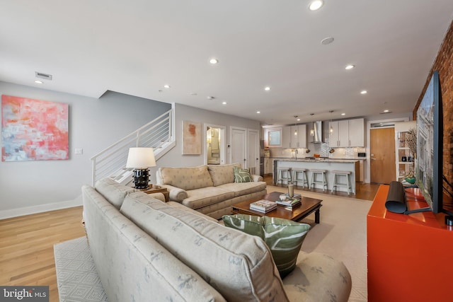 living area featuring recessed lighting, visible vents, stairway, light wood-type flooring, and baseboards