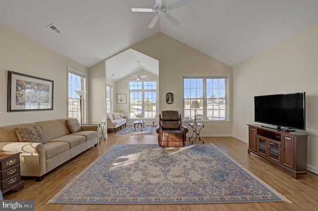 living room with visible vents, baseboards, light wood-style floors, high vaulted ceiling, and a ceiling fan