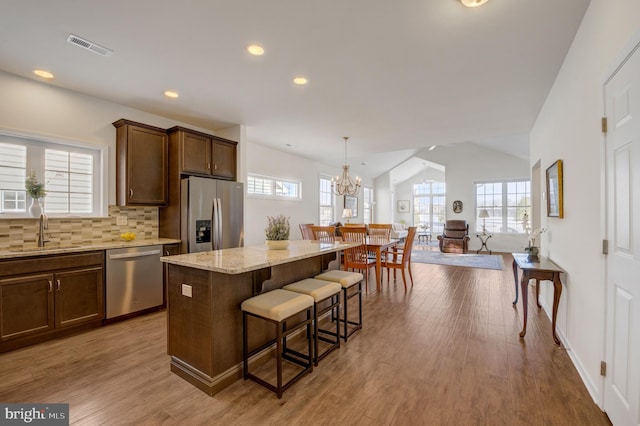 kitchen with a sink, a center island, stainless steel appliances, a breakfast bar area, and decorative backsplash