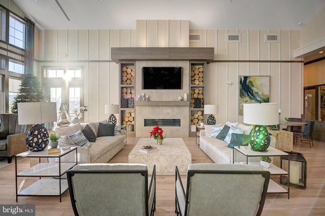 living room with a fireplace, a high ceiling, and light hardwood / wood-style flooring