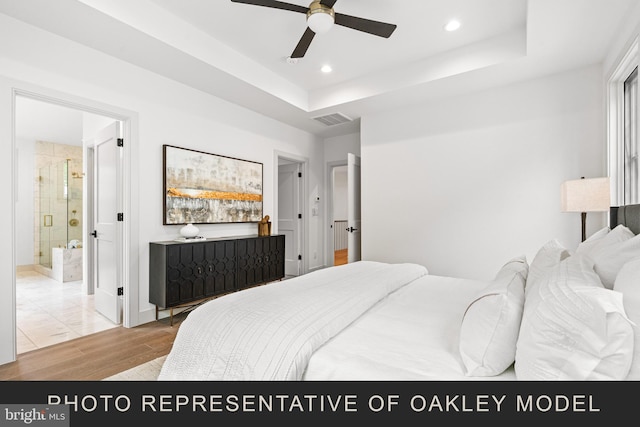 bedroom featuring ensuite bathroom, a raised ceiling, ceiling fan, and light hardwood / wood-style floors