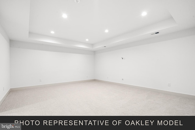 carpeted spare room featuring a tray ceiling