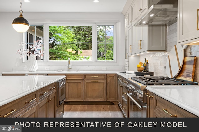 kitchen featuring sink, tasteful backsplash, light stone counters, and wall chimney exhaust hood