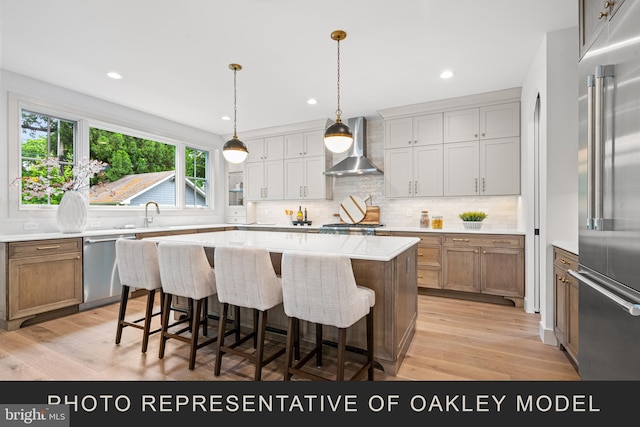 kitchen featuring decorative light fixtures, stainless steel appliances, wall chimney range hood, a kitchen island, and backsplash