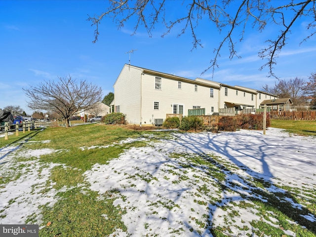 snow covered property featuring central AC unit and a lawn