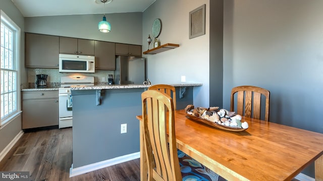 kitchen featuring gray cabinetry, hanging light fixtures, tasteful backsplash, lofted ceiling, and white appliances