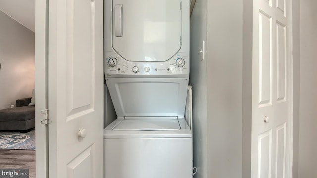 laundry area with wood-type flooring and stacked washer and clothes dryer