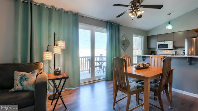 dining room with ceiling fan, dark wood-type flooring, and vaulted ceiling