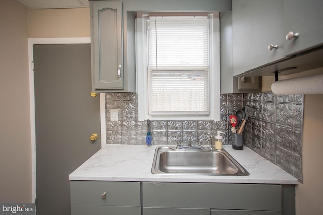 kitchen with gray cabinetry, sink, and tasteful backsplash