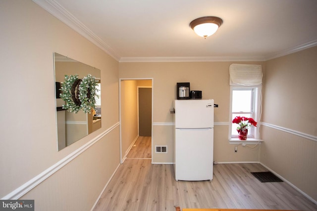 interior space with white fridge, light wood-type flooring, and ornamental molding