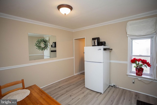 kitchen featuring light wood-type flooring, white refrigerator, and ornamental molding