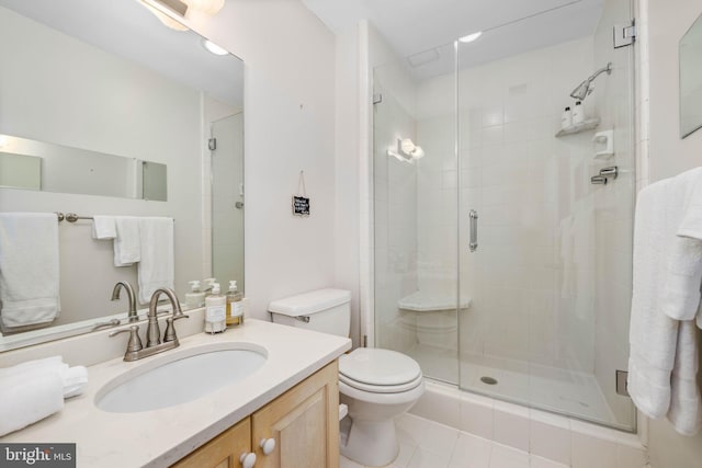 bathroom featuring tile patterned floors, a shower with door, vanity, and toilet