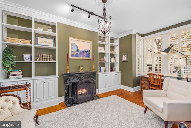 living area featuring a chandelier, crown molding, built in features, and light hardwood / wood-style floors