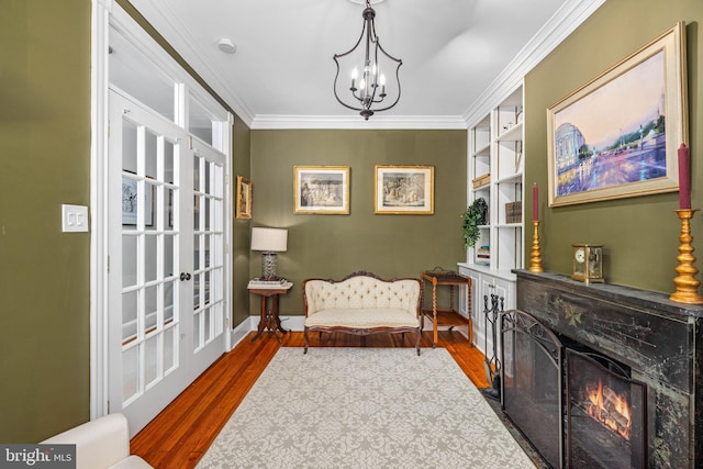 sitting room featuring hardwood / wood-style flooring, built in features, and ornamental molding