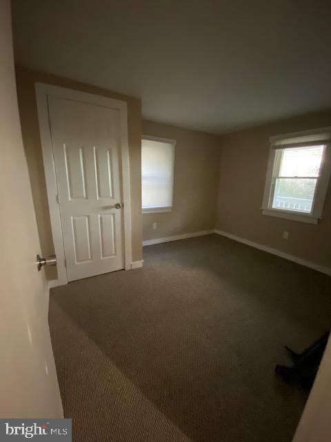 unfurnished room with dark carpet and a wealth of natural light