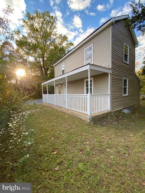 back of house with a porch and a yard