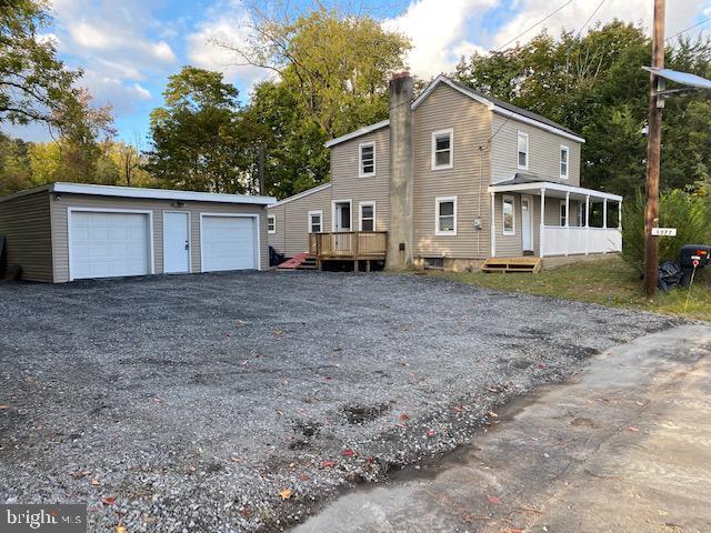 view of front of property featuring a garage, a deck, and an outdoor structure