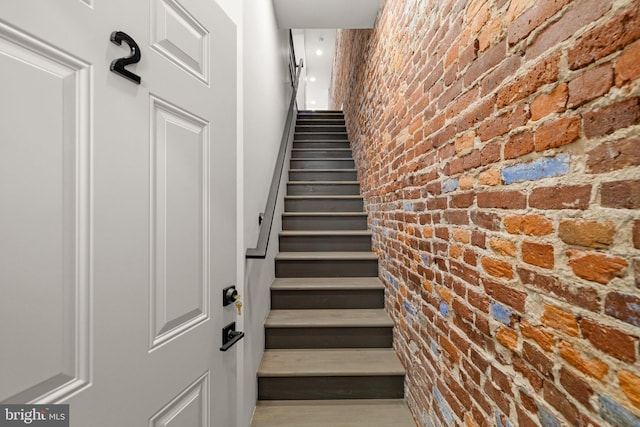 stairway featuring brick wall