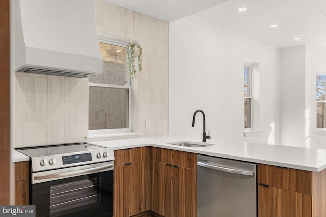 kitchen featuring sink, tasteful backsplash, premium range hood, kitchen peninsula, and appliances with stainless steel finishes