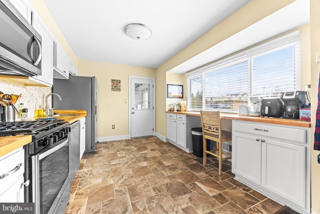 kitchen featuring wooden counters, sink, tasteful backsplash, white cabinetry, and stainless steel appliances