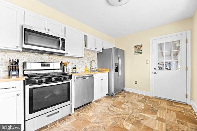 kitchen with decorative backsplash, sink, white cabinetry, and stainless steel appliances