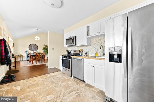 kitchen with hanging light fixtures, white cabinets, stainless steel appliances, and sink