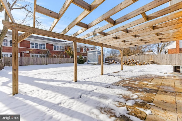 snow covered patio featuring a storage shed